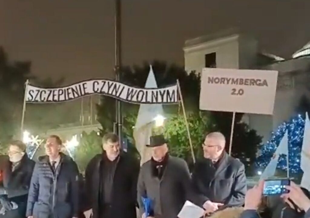 Posłowie Konfederacji w czasie protestu zorganizowanego [14 grudnia] przed Sejmem przez pewien czas stali na tle napisu “Szczepienie czyni wolnym”, stylizowanego na znajdujący się nad bramą obozu w Auschwitz napis “Praca czyni wolnym”. 